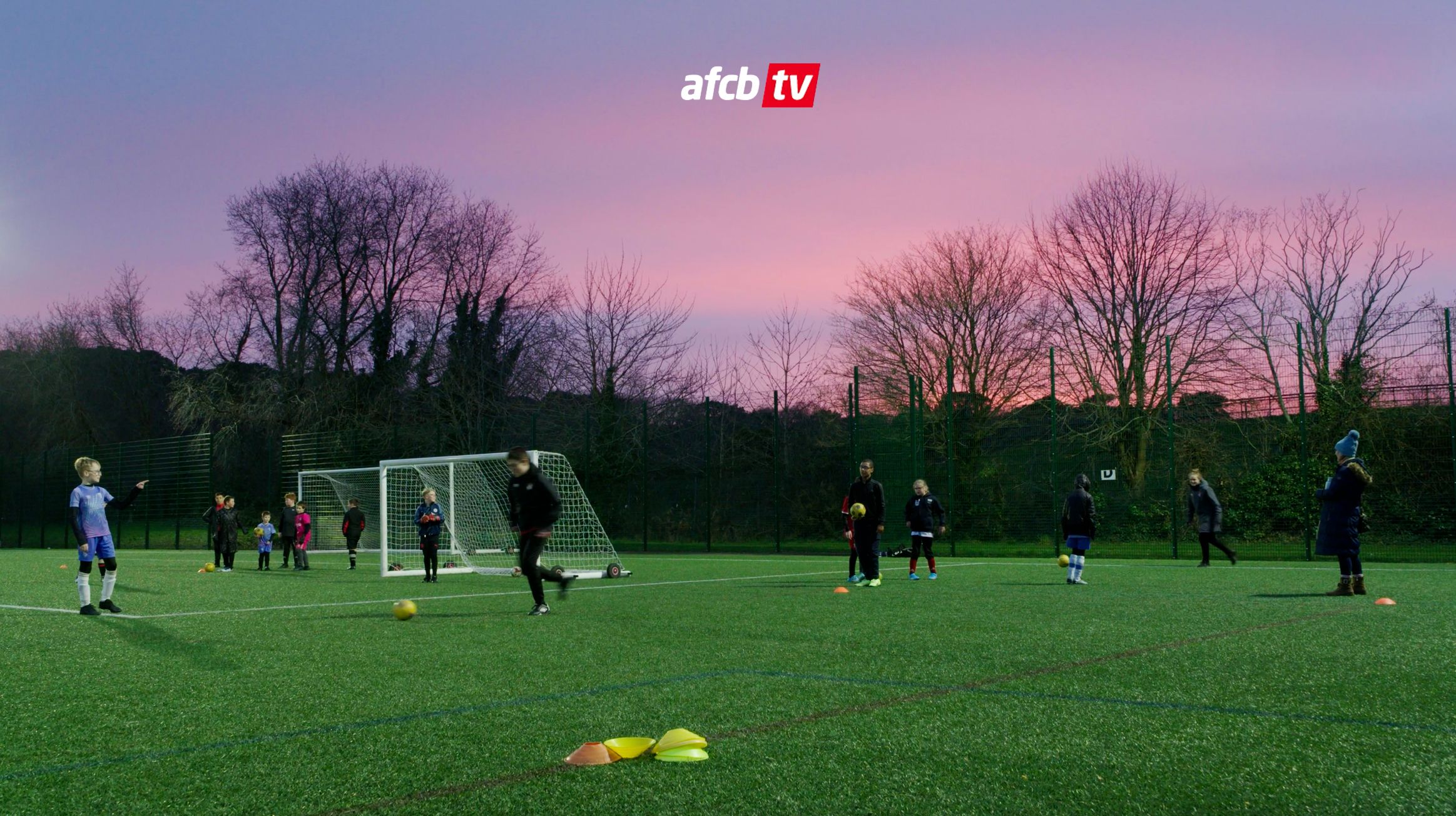SEN children playing football in front of a purple sun set