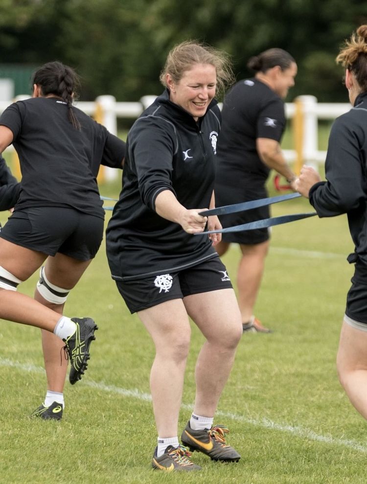 Rocky Clark running and holding one side of a gym band, another player is holding the other end