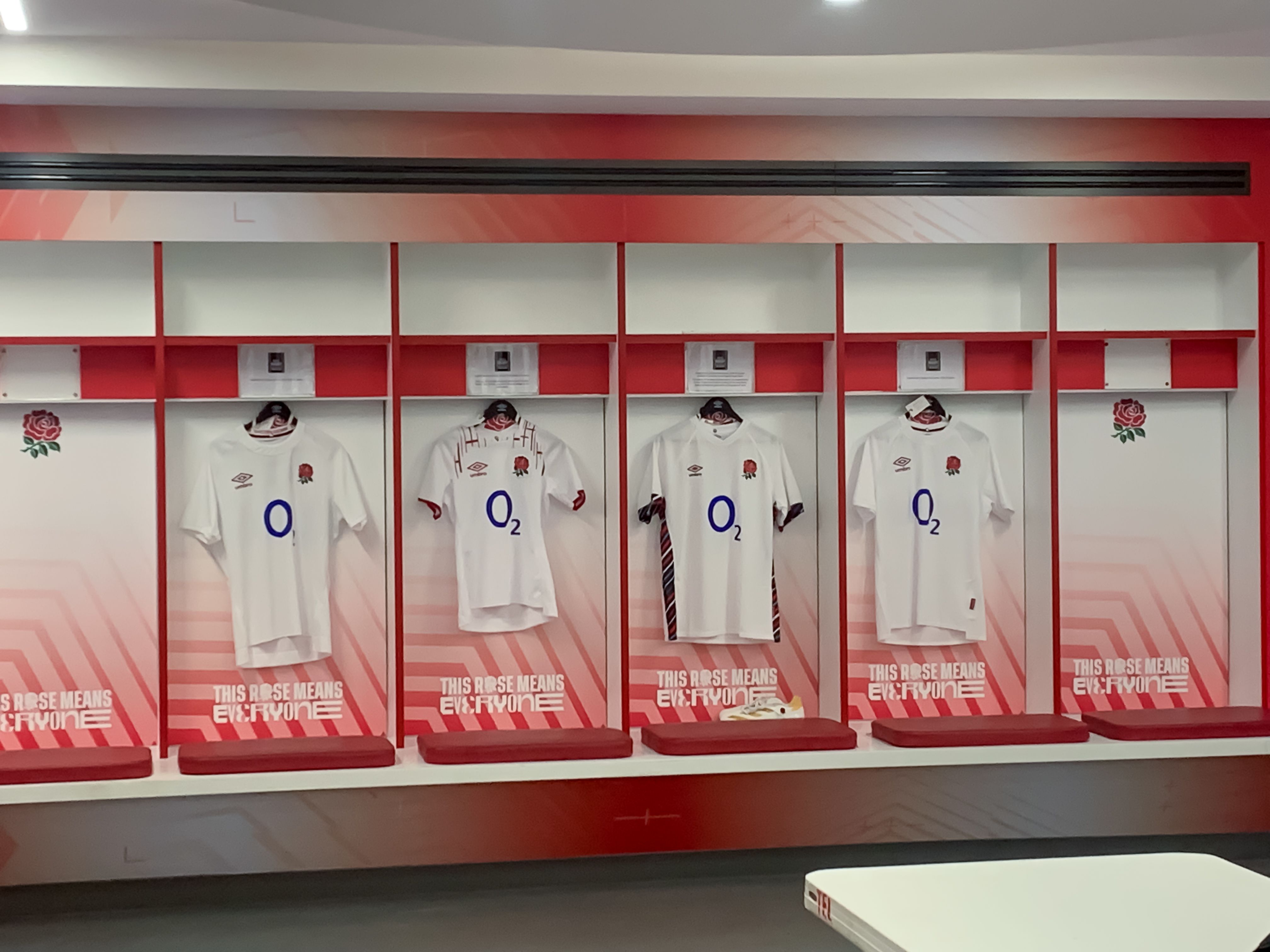 Four shirts hanging in cubbies in the England changing rooms at Twickenham Stadium.