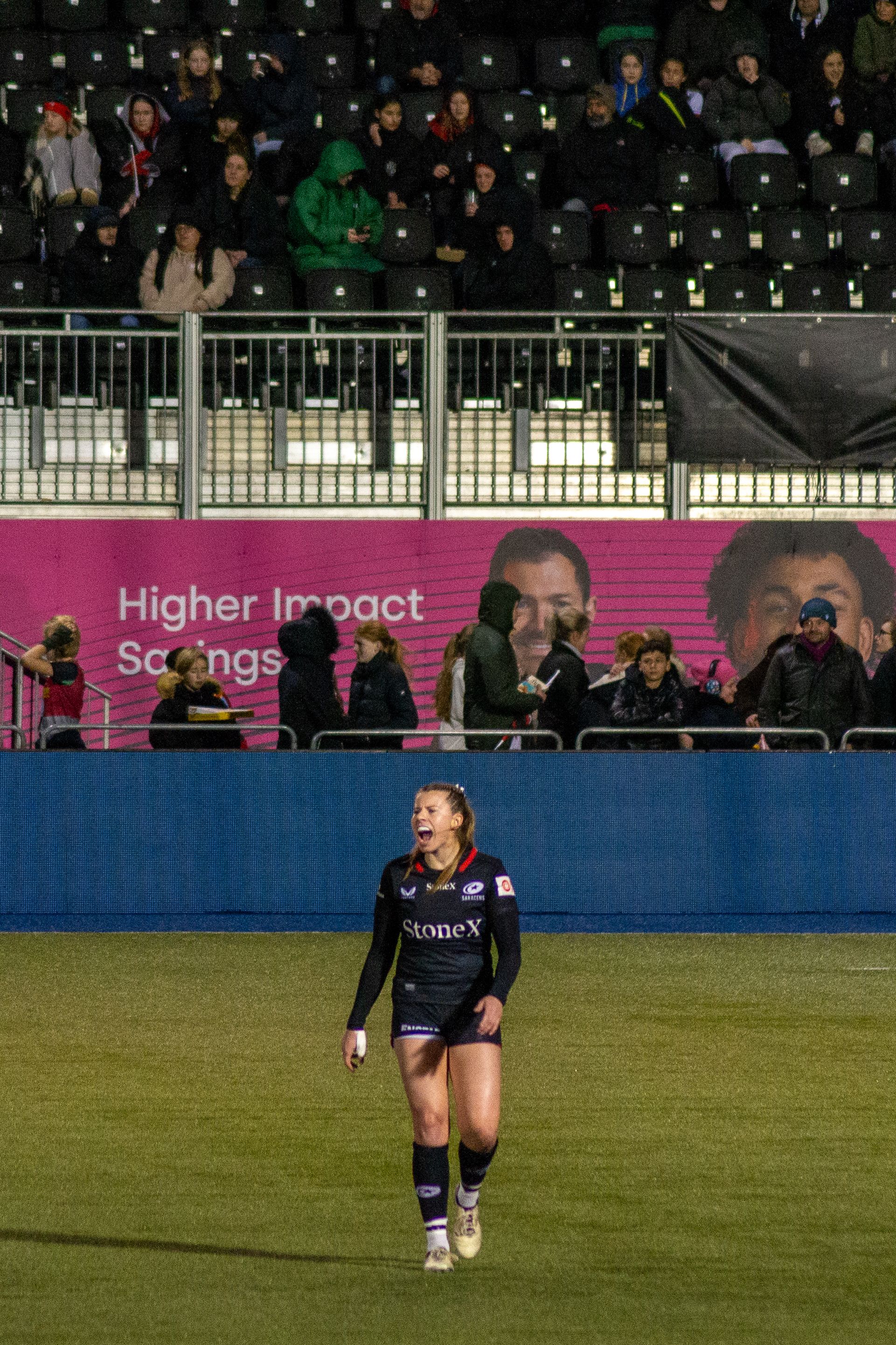 Zoe Harrison shouting on the pitch at StoneX stadium with a crowd behind her.