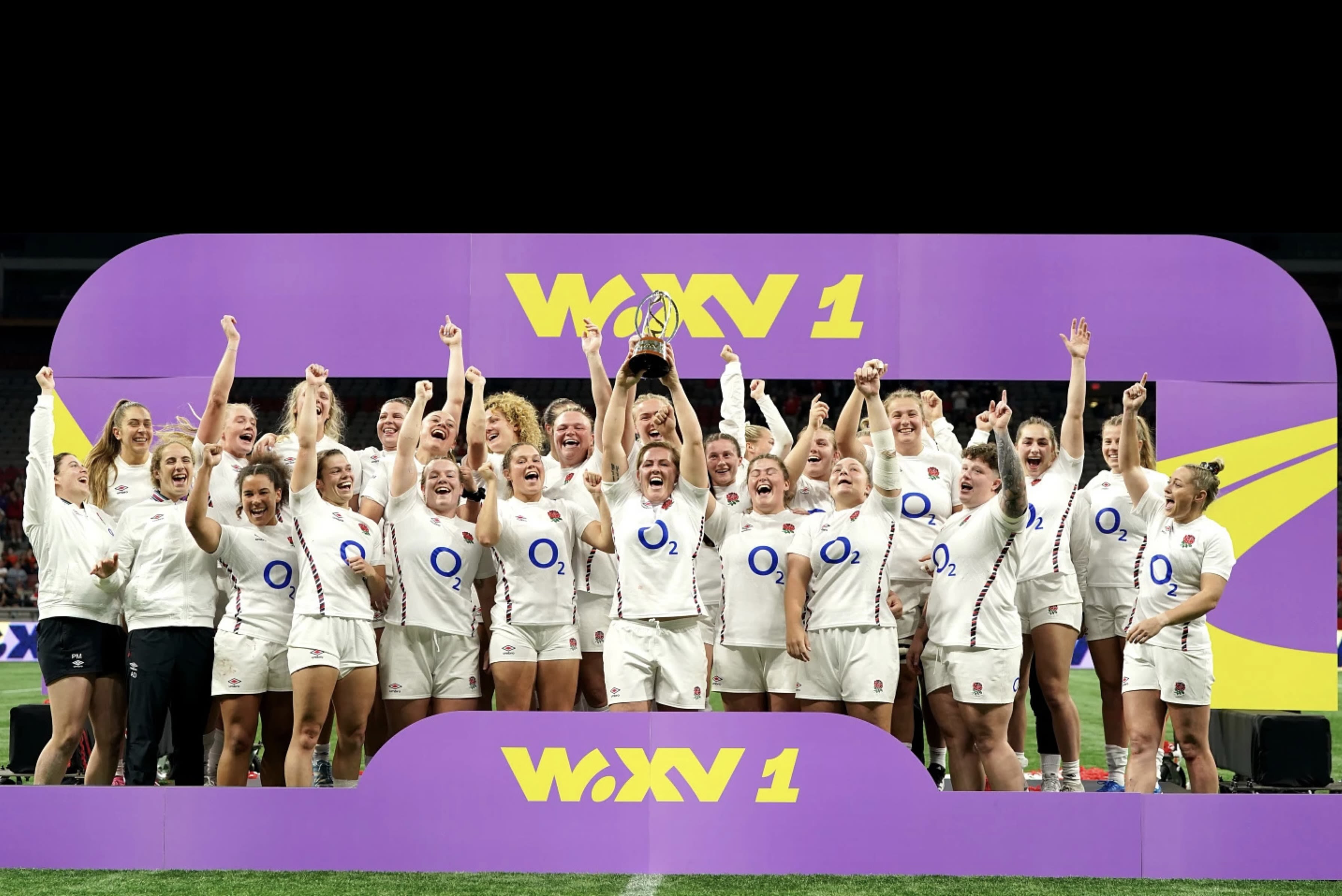 Red Roses team with their hands in the air. Marlie Packer is centre lifting a trophy.